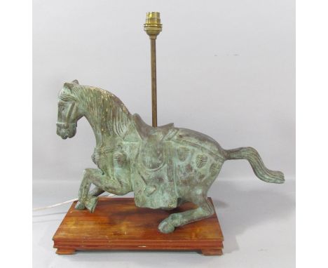 A bronzed Verdigris finished Chinese horse with lamp conversion, raised on a wooden plinth. 46cm wide, 