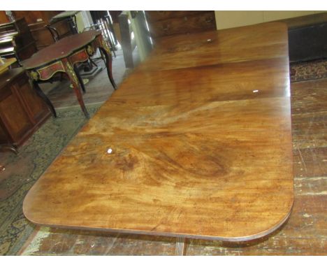 A Georgian mahogany twin pillar dining table with three additional leaves, the turned columns raised on reeded tripod support