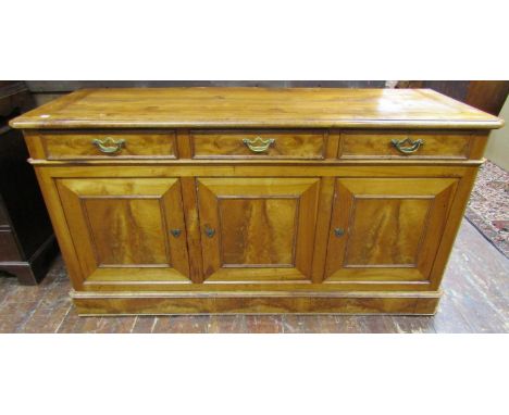 An early 19th century cherry wood side cupboard in a good honey colour, enclosed by three panelled doors, incorporating flame