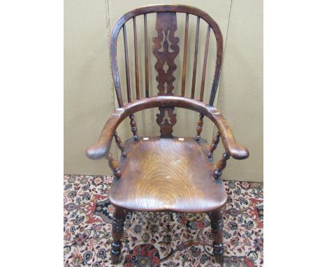 An early 19th century Windsor comb back elbow chair in elm and yew, the pierced splat in burr yew 