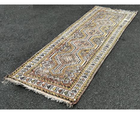 A faded wool Kazak type runner with four interlocking medallions in pink and yellow tones, 270cm x 100cm 