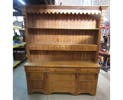 A Victorian style stripped pine farmhouse kitchen dresser, the base enclosed by an arrangement of cupboards and drawers with 