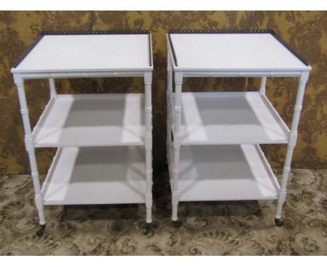 A pair of white painted Regency style three tier faux bamboo lamp tables, with pierced brass gallery sides, on brass castors,