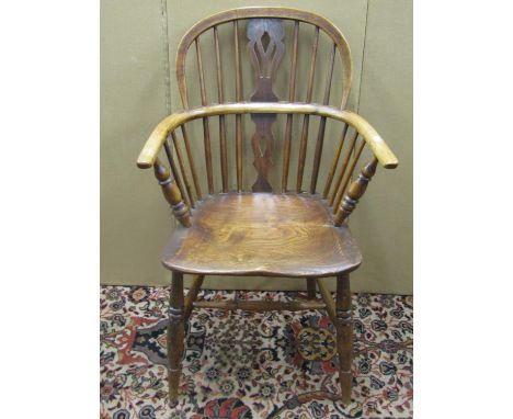 An early 19th century comb back Windsor elbow chair in elm and ash, with carved and pierced splat 