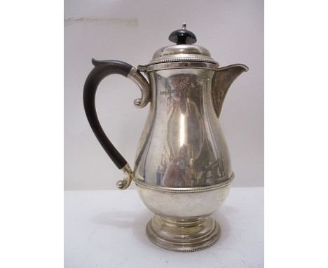 A silver hot water jug in baluster form with a beaded body and beading to foot and rim with Bakelite handle and knop finial b
