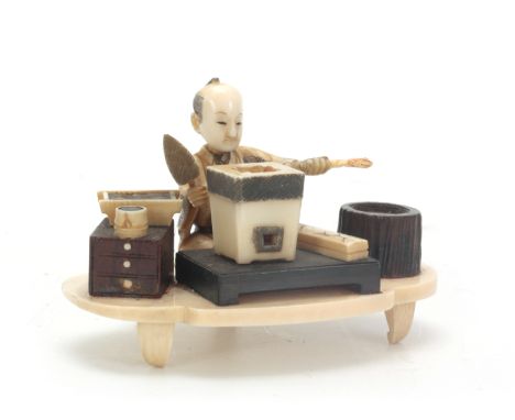 A JAPANESE MEIJI PERIOD IVORY AND STAINED IVORY OKIMONO the seated figure modelled as a brickmaker with mould, kiln and vario