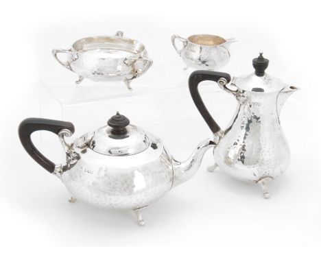 A SILVER ARTS &amp; CRAFTS DESIGN FOUR-PIECE TEA SERVICE having planished bodies and ebony handles, coffee pot measures 18cm 