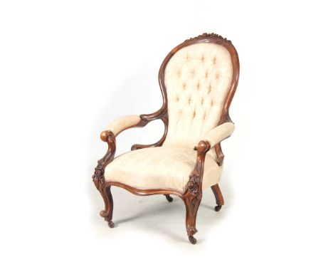 A VICTORIAN GENTLEMANS CARVED WALNUT BUTTON BACKED DRAWING ROOM CHAIR with carved frame and open arms; standing on cabriole l