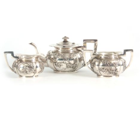 A 19TH CENTURY CHINESE THREE-PIECE SILVER TEA SERVICE of oblate panelled form with folded rims, each piece with  cavorting dr