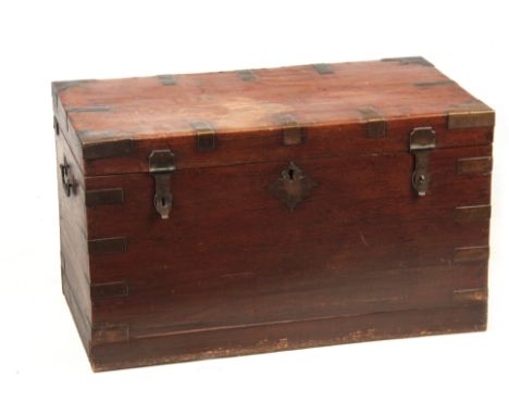 A 19TH CENTURY COLONIAL ANGLO INDIAN TEAK OFFICERS TRUNK having brass mounted corners and double-locked front with side carry