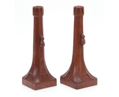 A PAIR OF EARLY ROBERT MOUSEMAN THOMPSON OAK CANDLESTICKS with triangular carved sconces and facetted ringed tapering stems o