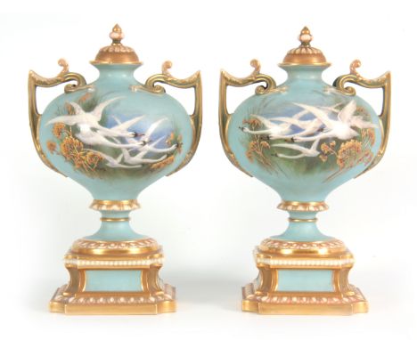 AN UNUSUAL SHAPEDA PAIR OF ROYAL WORCESTER LIDDED CABINET VASES BY CHARLES BALDWYN having bulbous bodies with shaped side han