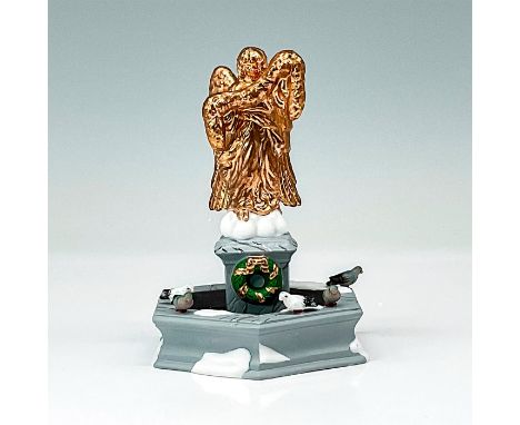 A copper angel statue is place on top of a stone base within a fountain. There are birds and snow decorated through the fount