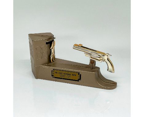 The cast metal bank features a cowboy standing in front of a saloon. Put a coin on the barrel of the gun and pull the spring-