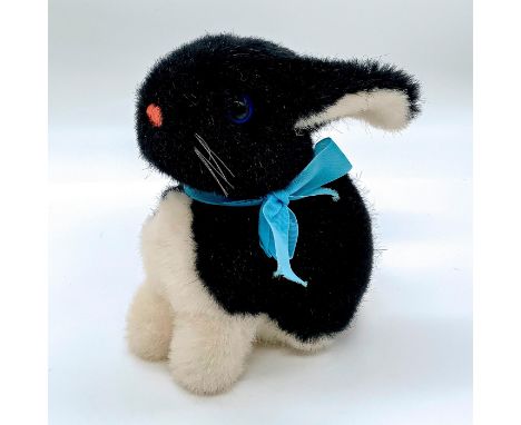 In black and white coloration, blue colored eyes, pink nose, with baby blue ribbon around neck. Steiff metal tag to ear. Dime