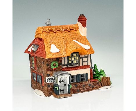 Department 56 figurine depicting "Betsy Trotwood's Cottage". A quaint brown, white and terracotta cottage with added pine tre