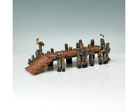This figure shows a long wooden pier bridge with an adjustable end. A seagull is seen sitting on one of the posts and there i