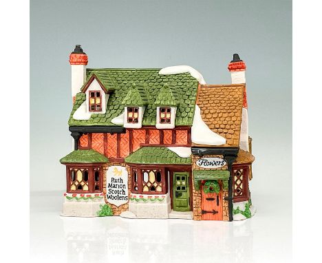 This figure shows a rustic village shop. The building is made of green, red, and brown colored stone and decorated with winte