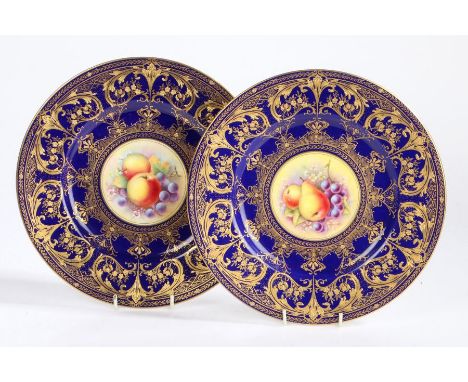 Pair of Royal Worcester porcelain plates hand decorated by T. Nutt and R. Price, the blue ground with gilt foliate and scroll