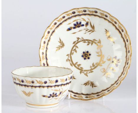 A Worcester porcelain tea bowl and saucer, late 18th Century, decorated with gilt and blue flowers, both with crescent C in b