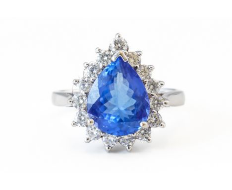 A TANZANITE AND DIAMOND CLUSTER RINGCentrally claw set with a pear cut tanzanite weighing an estimated 2.95 carats, with a su