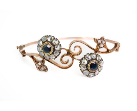 A GOLD, SAPPHIRE AND DIAMOND BANGLEIn a twin cluster crossover design, each cluster mounted with a round cut central sapphire