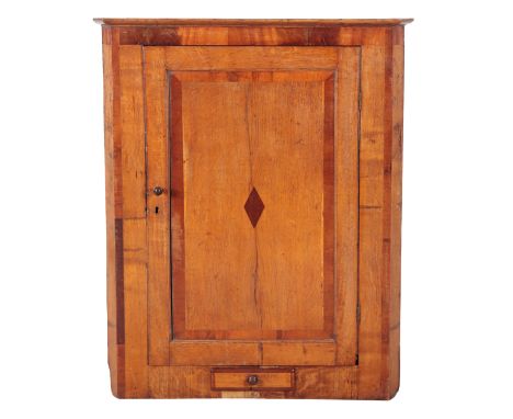 A GEORGE III OAK AND CROSSBANDED CORNER CUPBOARD the moulded pediment over a single panelled door, opening to a shelved inter