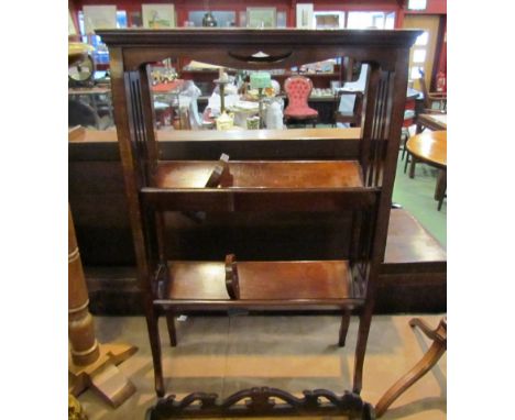 In the manner of 'Liberty &amp; Co' an arts &amp; crafts mahogany two tier book trough with fret work decoration &amp; slider