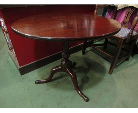 A George III mahogany circular tilt top wine table on a turned column and tripod base 75cm in diameter and 64cm high