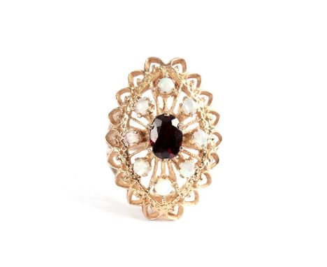 A garnet and opal cluster ring, the central oval garnet within a border of eight circular cabochon opals, in openwork marquis