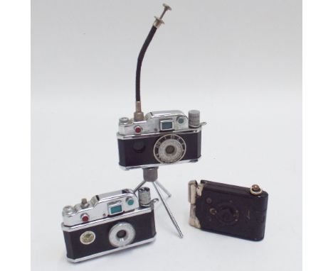 3 vintage camera lighters, one with tripod stand 