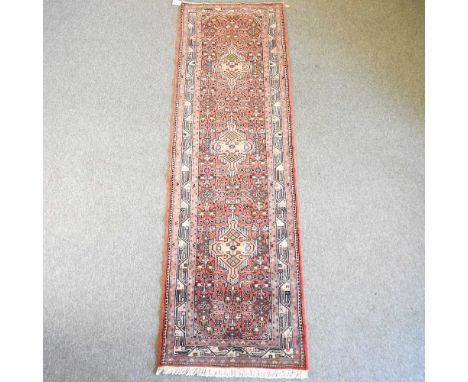 A Persian runner, with three ivory medallions, on a red ground, 285 x 87cm