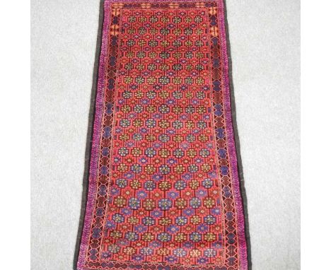 A Persian runner, with all over designs, on a red ground, within multiple borders, 240 x 120cm