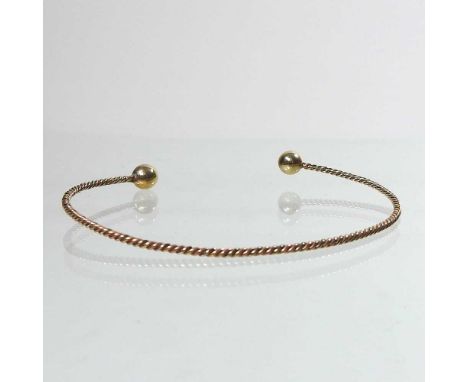 A three colour gilt bangle, of twisted design, unmarked, 3.5g, 7cm wide