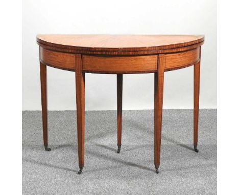 A George III style satinwood half round folding card table, with a radially veneered hinged top, on square tapered legs102w x