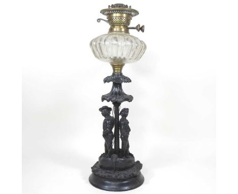 An unusual 19th century cast iron oil lamp base, the scrolled support, decorated with two figures, below a cut glass reservoi