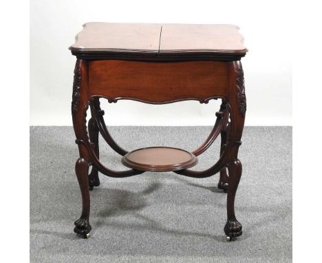 An early 20th century surprise card table, the shaped dual hinged top, revealing a rising fitted interior, on a carved base, 