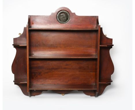 A mahogany wall shelf possibly retailed by Liberty &amp; Co, shaped rectangular back, three central shelves flanked by two si