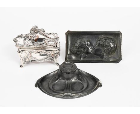 An Art Nouveau pewter inkwell, elliptical section, cast in low relief with panels of flowers and secessionist drop motif, ins