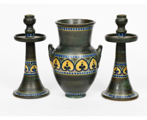 A Liberty &amp; Co vase and candlestick garniture,  probably made by Gouda, painted with a band of heart-shaped foliage in ye