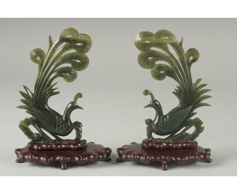 A PAIR OF CHINESE CARVED SPINACH GREEN JADE PEACOCKS ON ORIGINAL WOODEN STANDS, 18cm high.