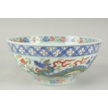 A CHINESE WUCAI PORCELAIN BOWL, painted with dragons and flora, 20.5cm diameter.