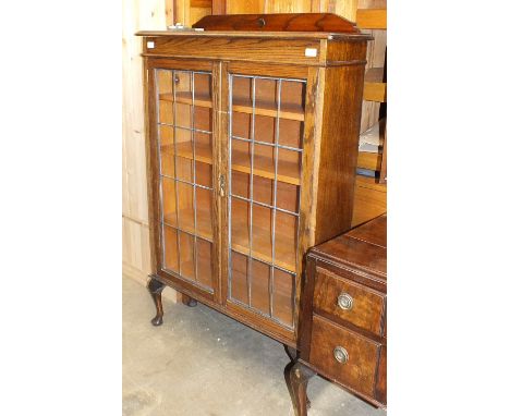 An oak bookcase, the rectangular top above a pair of leaded-light doors, on cabriole legs, 92cm wide, 137cm high.