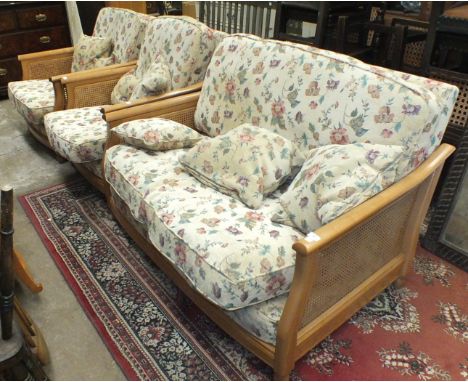 A modern Ercol Bergère-style light wood two-seater settee with cane sides and loose cushions and two matching armchairs.