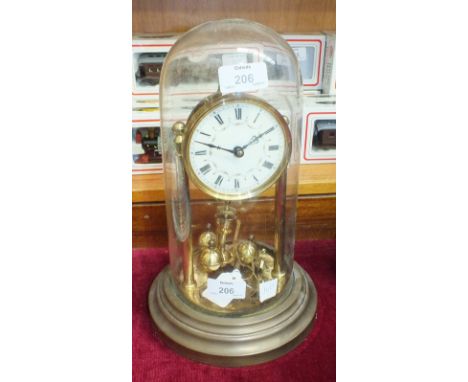 A brass 400-day clock, the dial with Roman numerals under glass dome, on circular base, 31cm high overall.