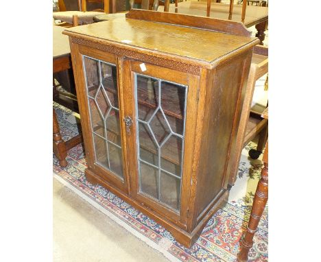 An oak low bookcase fitted with a pair of leaded-light doors, 70cm wide, 92cm high, an oak tea trolley and a low oval mahogan