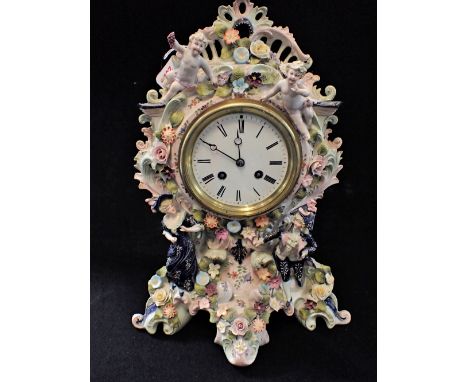 A 19TH CENTURY DRESDEN MANTEL CLOCK, with floral encrusted decoration decorated with figures and cherubs, with a white enamel