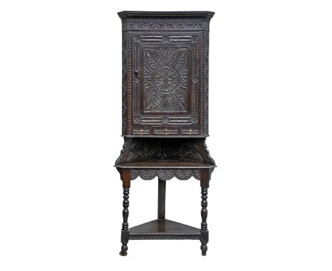A Victorian carved oak corner cupboard and associated stand, profusely decorated with foliage, the stand on turned legs with 