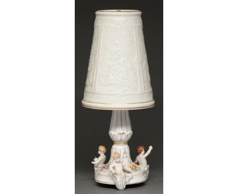 A German porcelain table lamp and shade, the base decorated with three cherubs, 51cm h  Minor chips and losses to base