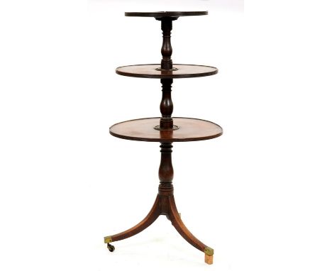 A George III mahogany dumb waiter, of three tiers with baluster shaft, on tripod with plain brass capped castors, 135cm h  Ol
